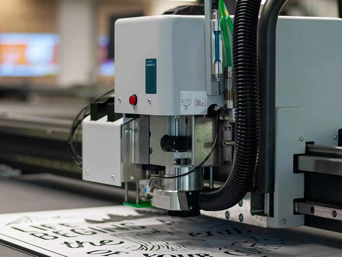 Kongsberg X с головкой MultiCUT-HP: крупный план инструмента и обработанного листа. Головка MultiCUT-HP цифрового стола Kongsberg X над обработанным листом